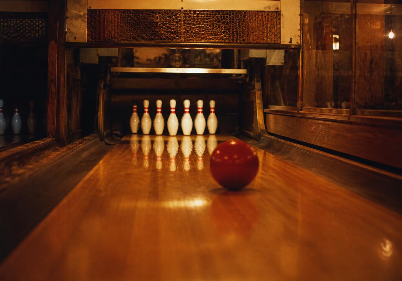 Warm vintage view of a Pin Center Bowl lane with a red ball rolling toward the pins